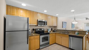 A modern kitchen with wooden cabinets, stainless steel appliances, and a granite countertop.