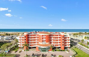 A multi-story hotel with a central courtyard, located near a beach with a clear view of the ocean. - Family-Friendly 2BR Condo with Pool Access (Treasure Island)