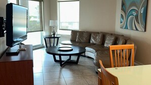 A living room with a TV, a dining table, a sofa, and a ceiling fan.