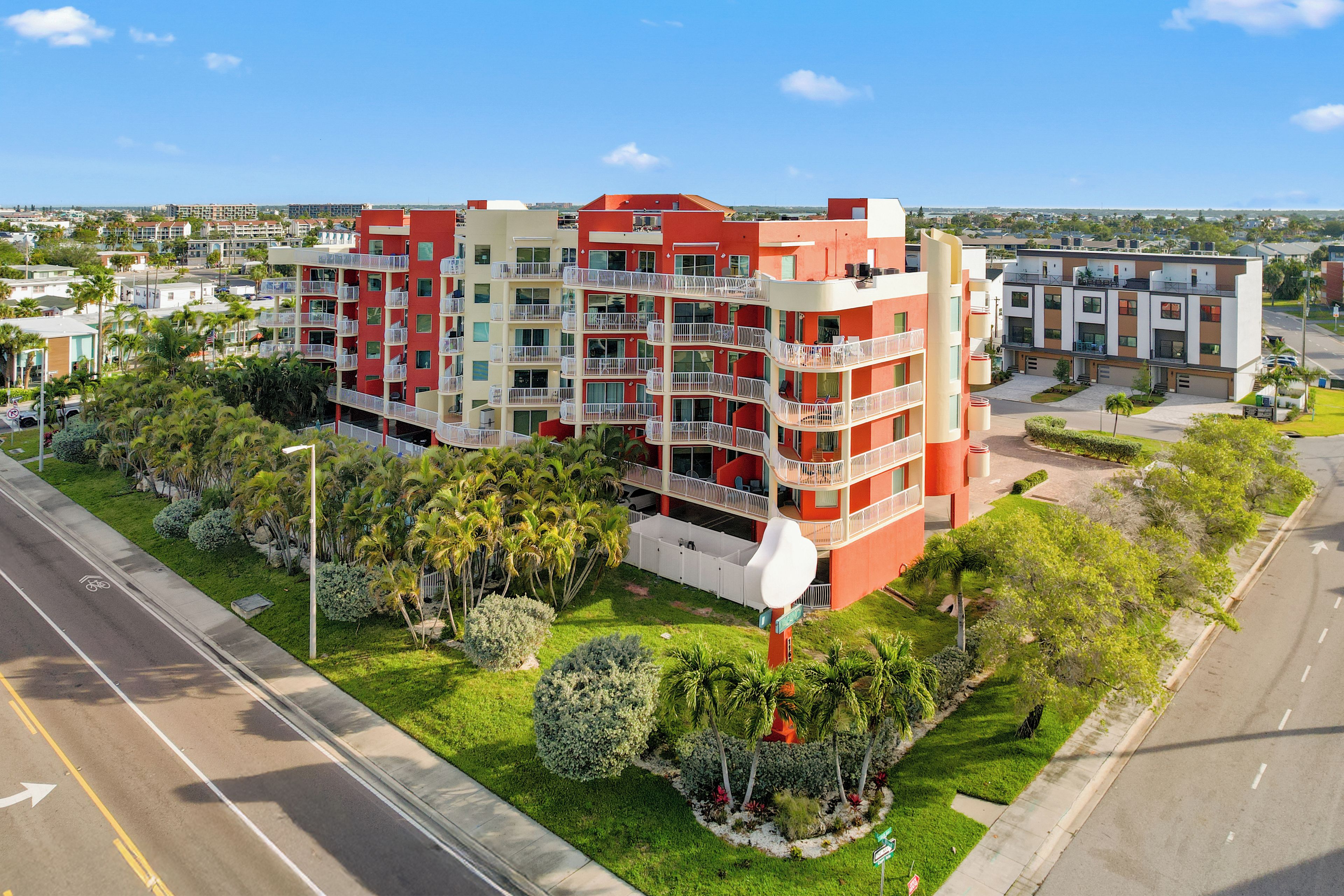 Un hôtel à plusieurs étages doté de balcons, d’un parking et offrant une vue sur un ciel dégagé.