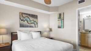 A neatly made bed with white linens, two bedside lamps, and abstract wall art. - Condo: 2BR/2BA by Beach, W/D, Pool & Parking (Treasure Island)
