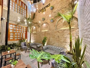 A cozy lounge area with a brick wall, a sofa, and various plants. - Colonia Suites 722 by Wellcome (Bogotá)