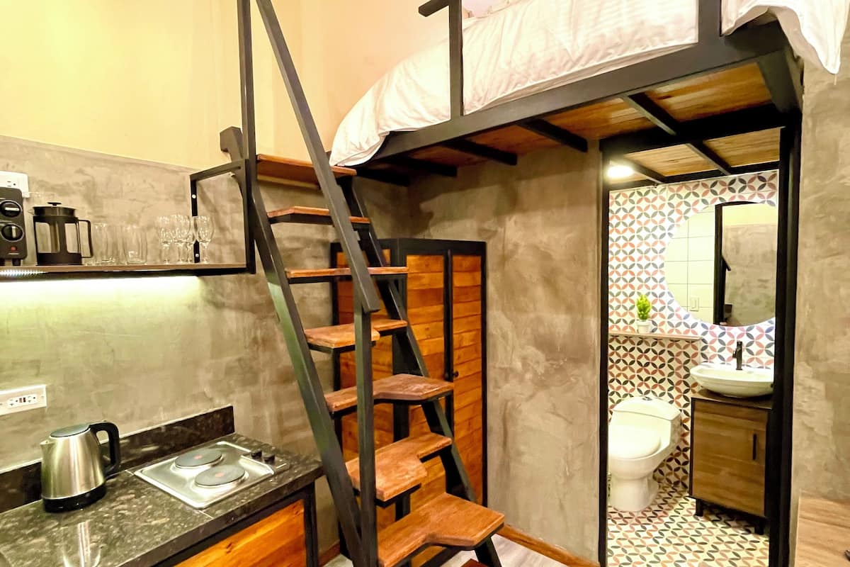 A compact kitchen with a wooden staircase leading to a loft bedroom.