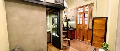 A compact living space with a loft bed, a dining area, and a kitchen.