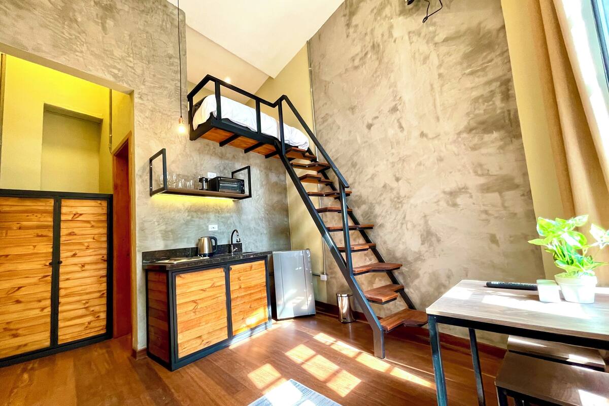 A modern kitchen with a wooden cabinet, a built-in oven, and a staircase leading to an upper level.