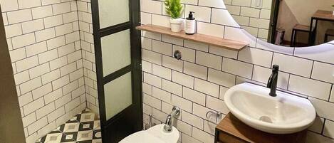 A bathroom with a white toilet, a sink with a mirror above it, and a shelf with toiletries.