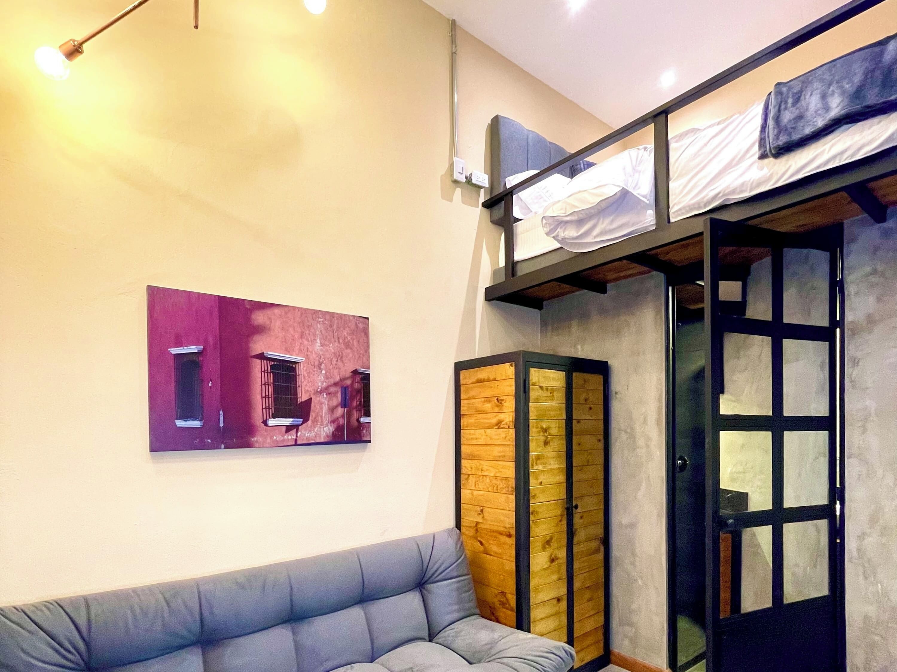 A room with a bunk bed, a cushioned seating area, a wooden cabinet, and a wall-mounted picture.