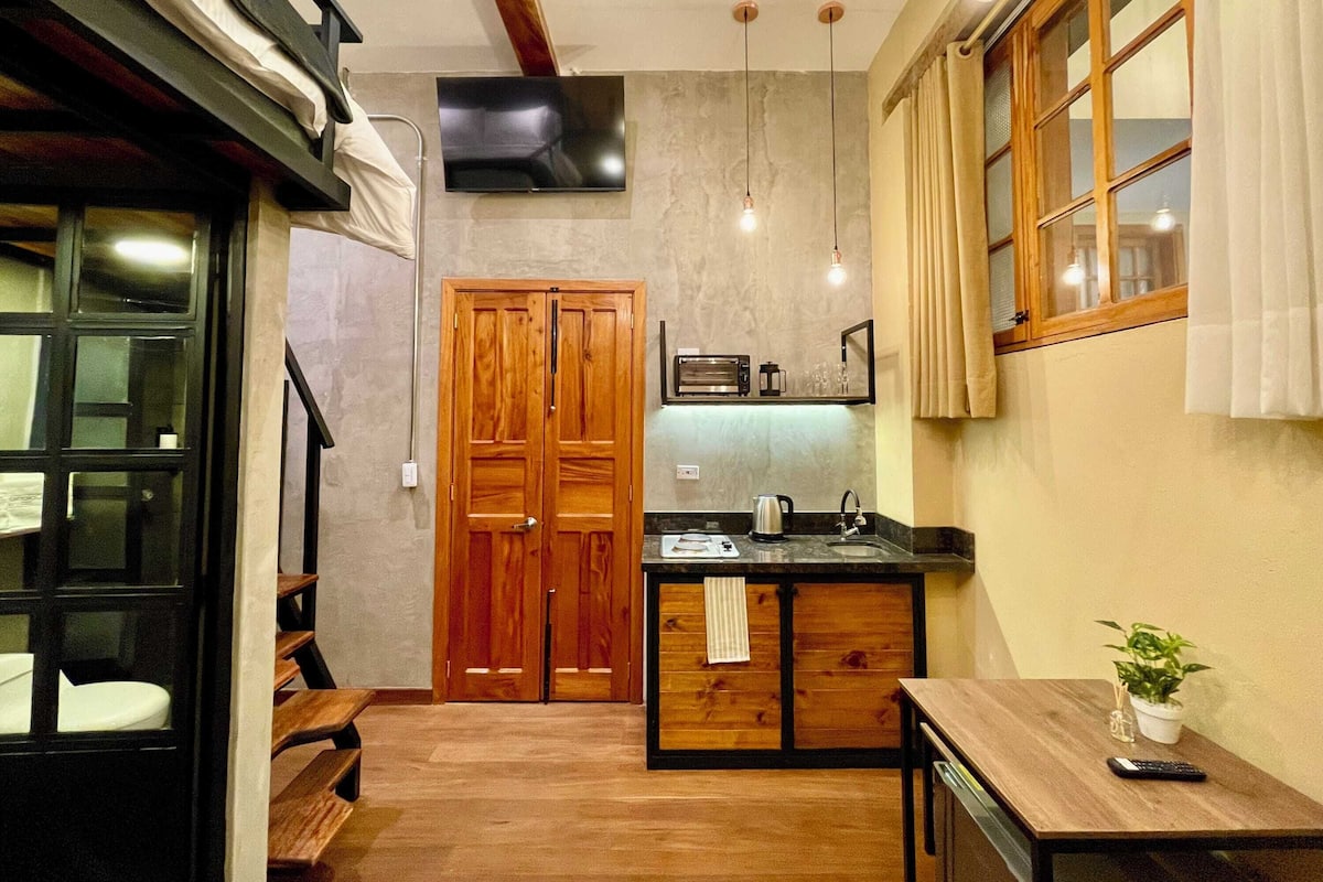A compact kitchen with a wooden door, a built-in microwave, and a small countertop.
