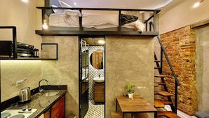 Ein kompaktes Studioapartment mit Küchenzeile, Essbereich und Schlafgalerie mit Blick auf das Badezimmer.