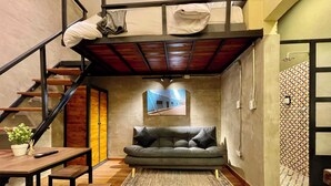 Ein kompakter Wohnraum mit Schlafkoje, einer Couch, einem Esstisch und einer Treppe.