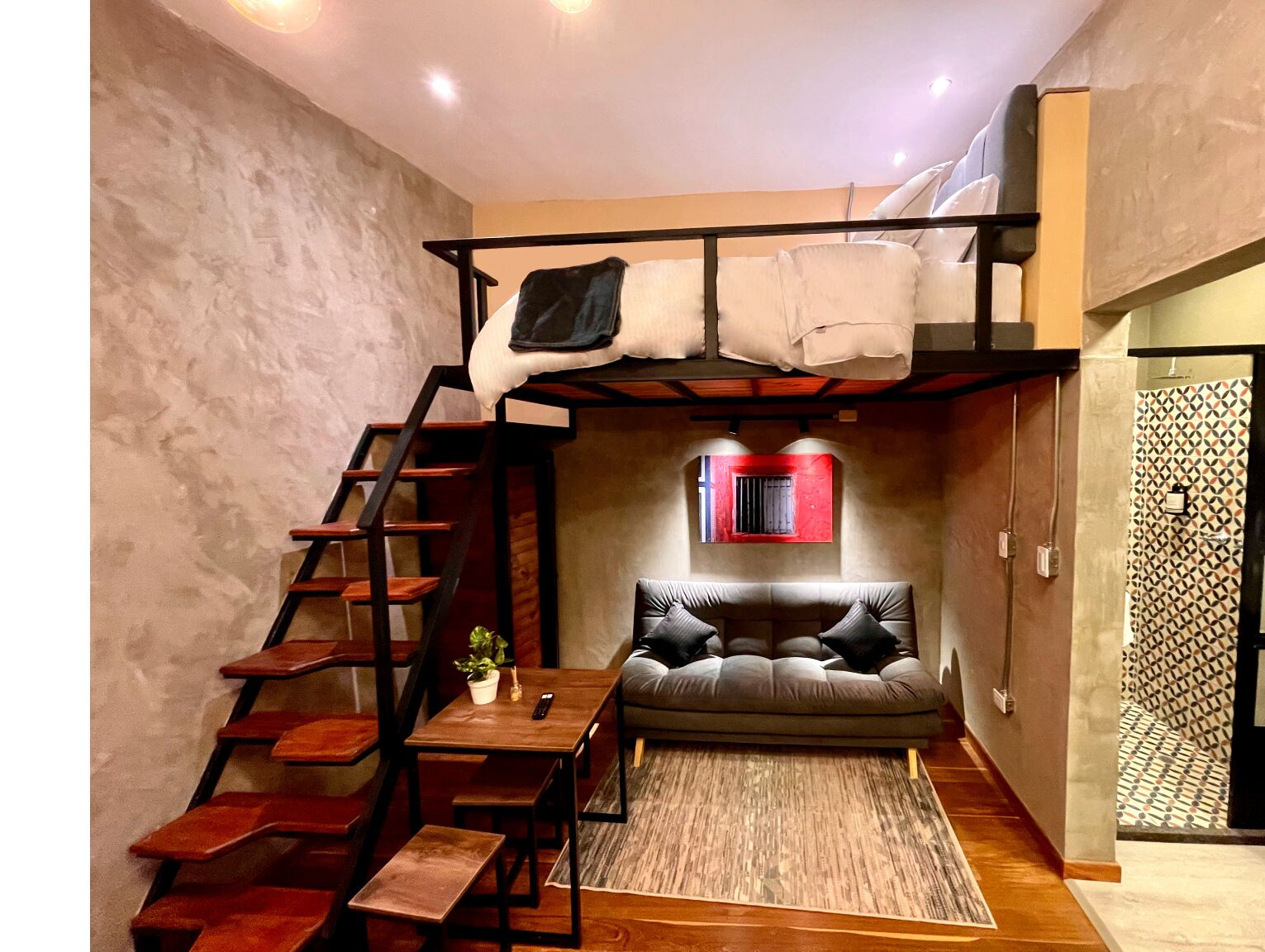 Een kamer in loftstijl met een stapelbed, een eettafel en een bank.