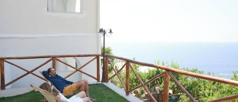 A couple relaxing on a wooden deck with a view of the sea.