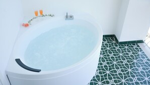 A white bathtub with a green patterned floor, a rose, and two glasses of orange liquid. - Pezz Pezz Amalfi Coast Suites (Praiano)
