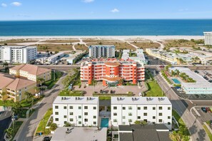 A coastal hotel with multiple buildings, a parking lot, and a view of the beach and ocean. - Seaside 2BR Condo: Pool, Parking, & Beach (Treasure Island)