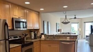 A modern kitchen with wooden cabinets, stainless steel appliances, and a tiled floor.