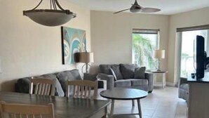 A spacious living area with a dining table, sofas, and a ceiling fan.