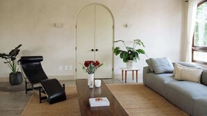 Ein modernes Wohnzimmer mit einer Couch, einem Lounge-Sessel, einem Couchtisch und einem Blumentopf.