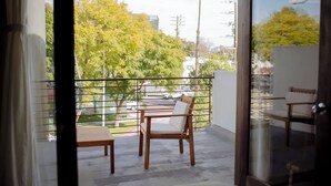A balcony with a wooden chair and table, overlooking a residential area with trees and buildings. - Designer's Apartment in the Heart of West Hollywood (West Hollywood)