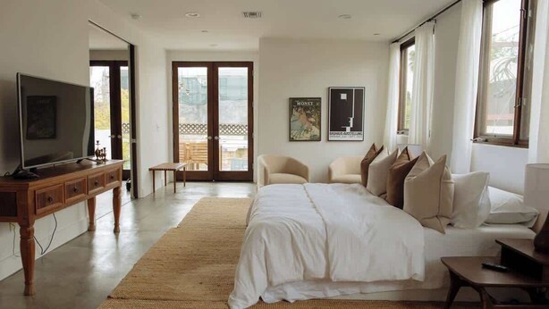 Ein modernes Hotelzimmer mit einem großen Bett, einem Fernseher, einer Holzkabine und einem Balkon mit Blick.