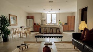 Eine moderne Küche mit einer zentralen Kochinsel, Barhocker und einem Essbereich mit Tisch und Stühlen.