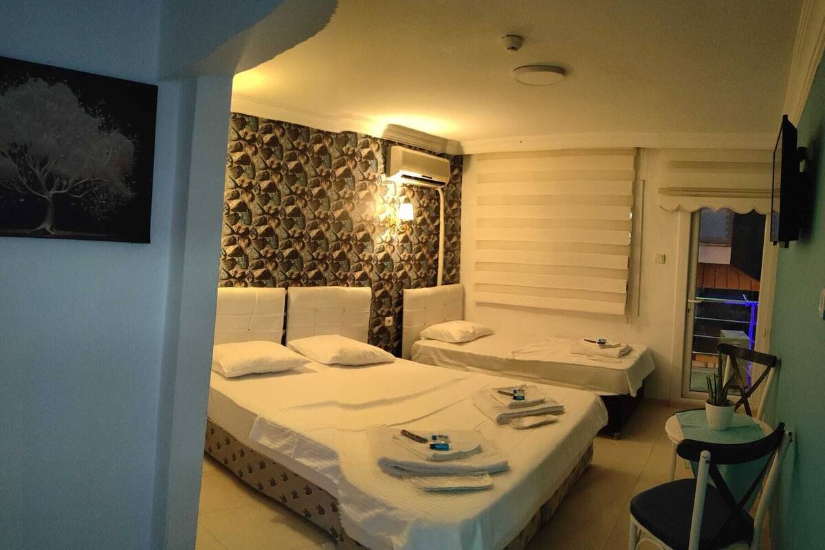 Une chambre d’hôtel avec deux lits, un mur en pierre, un téléviseur fixé au mur et une petite table avec une chaise.