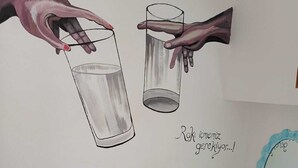 A wall with a mural of hands holding glasses, and a sign that reads "Raki icmemiz ceserlik...!" - Dafne Butik Pansiyon (Karaburun)