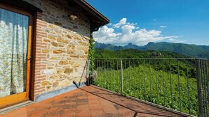 A stone building with a balcony overlooking a mountainous landscape. - Casa Vacanze La Casala (Fivizzano)