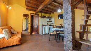A rustic interior with a wooden ceiling, a dining area with a table and chairs, and a kitchen area with a microwave. - Casa Vacanze La Casala (Fivizzano)