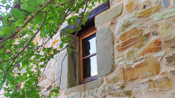 A stone building with a window and a tree branch in front. - Casa Vacanze La Casala (Fivizzano)