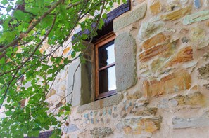 A stone building with a window and a tree branch in front. - Casa Vacanze La Casala (Fivizzano)