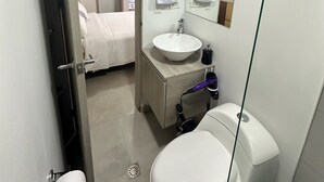 A modern bathroom with a toilet, sink, and mirror. - Encantador Loft en Medellín (Medellin)