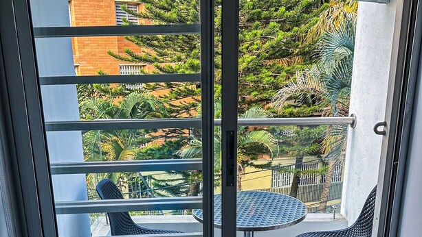 A balcony with a sliding glass door, a small table, two chairs, and a fan. - Encantador Loft en Medellín (Medellin)