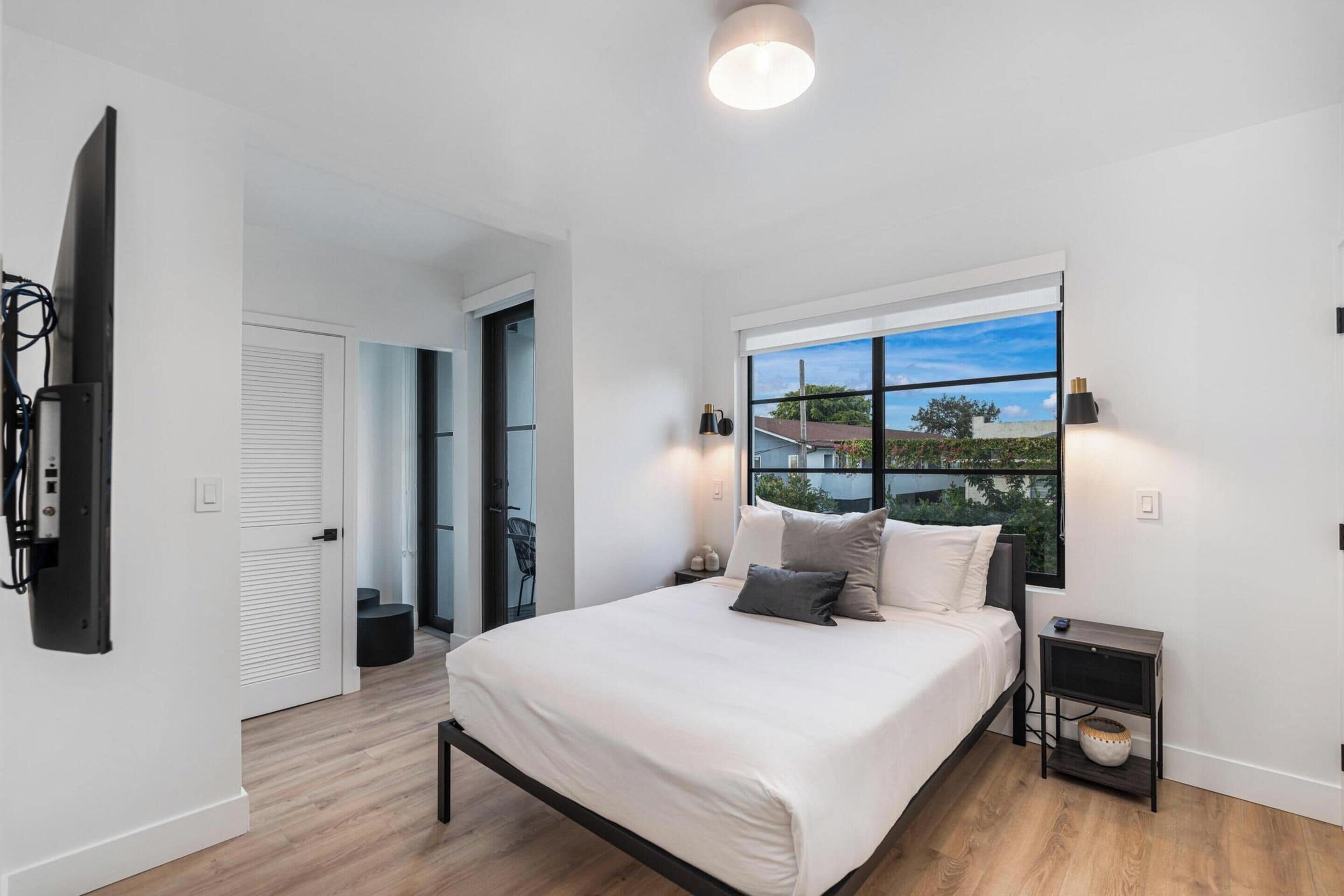 Une chambre à coucher avec un lit, une table de chevet et une fenêtre donnant sur l’extérieur.