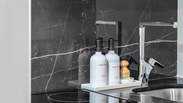 Une cuisine dotée d’un plan de travail en marbre noir, d’un évier en acier inoxydable et d’un four encastré avec des boutons de commande.