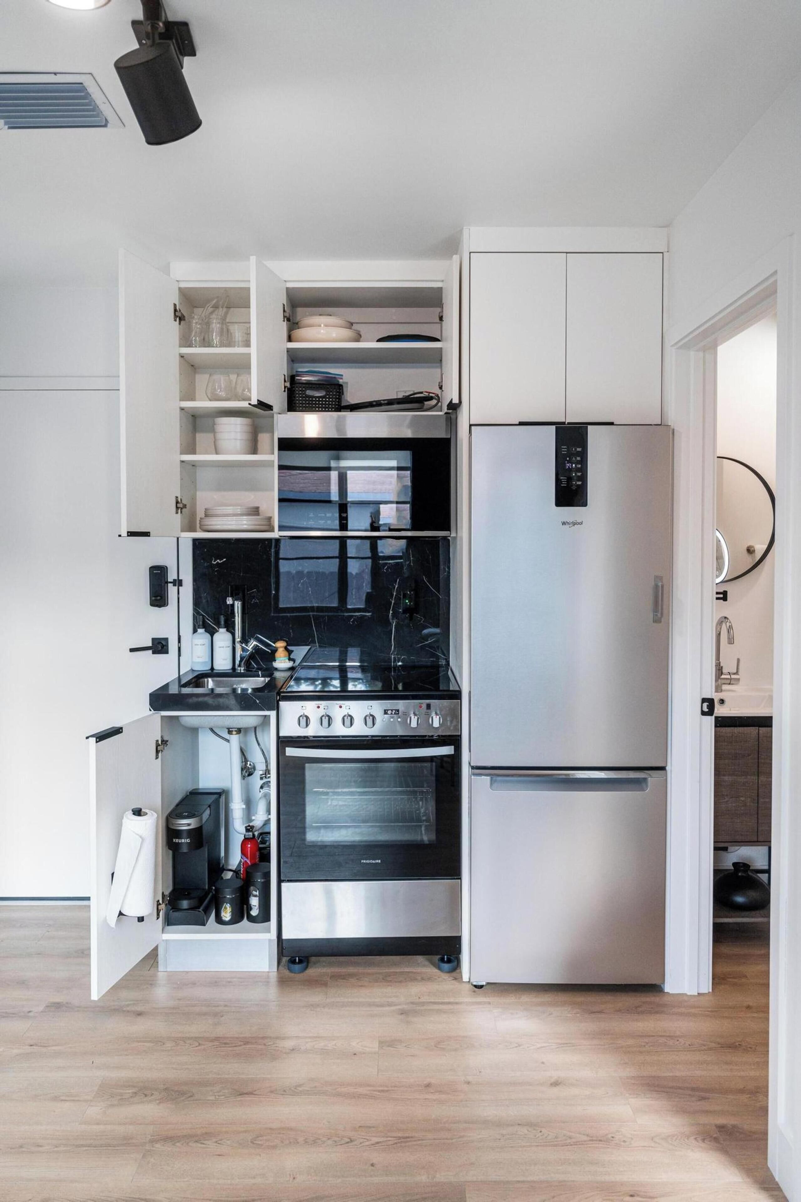 Una cucina compatta con forno integrato, frigorifero in acciaio inossidabile e microonde.