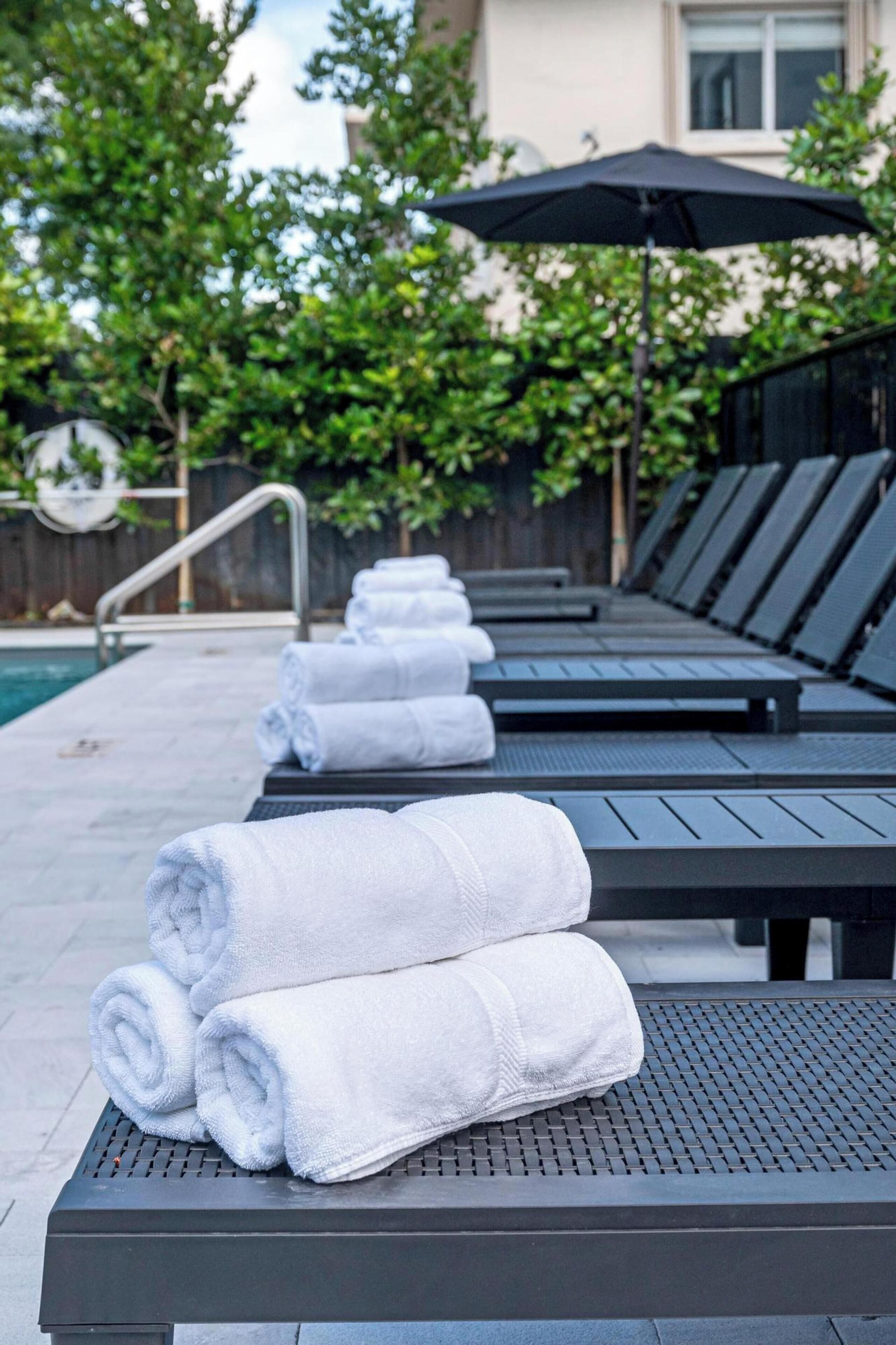 Un área junto a la piscina con sillones de descanso y toallas.