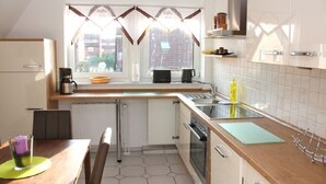 A compact kitchen with a window, a microwave, a kettle, and a sink.