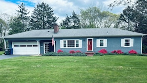A single-story house with a garage, a red door, and a small front porch. - Charming 3-bedroom ranch 1 minute from Mohegan Sun. (Montville)