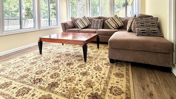 A spacious living room with a large sectional sofa, a wooden coffee table, and a patterned rug. - Charming 3-bedroom ranch 1 minute from Mohegan Sun. (Montville)
