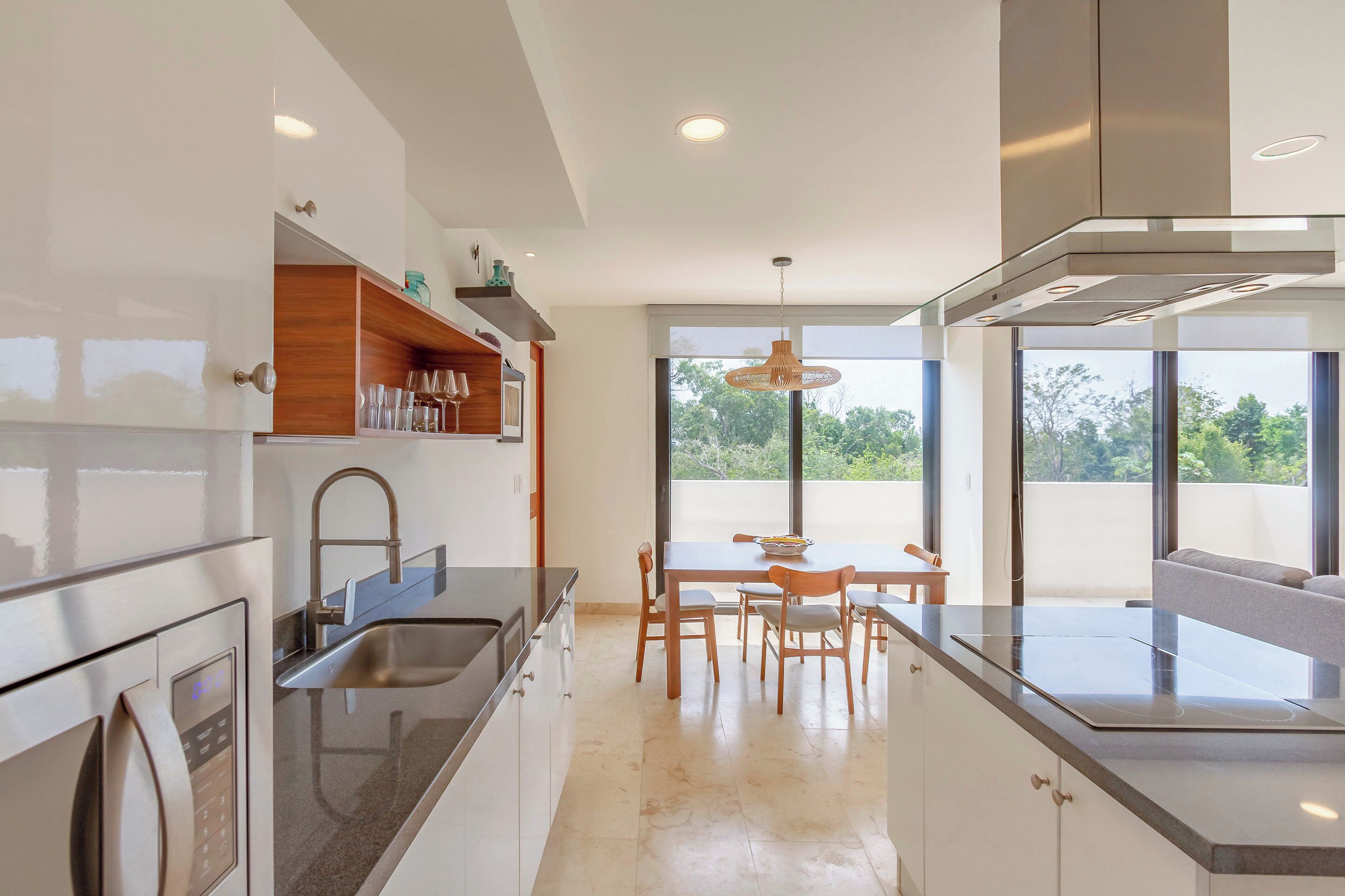 A modern kitchen with a built-in oven, stainless steel appliances, and a dining area with a table and chairs.