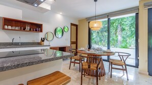 A modern kitchen with granite countertops, wooden chairs, and a dining table set for four. - Tropical Retreat Pools Golf Gym  (Akumal)