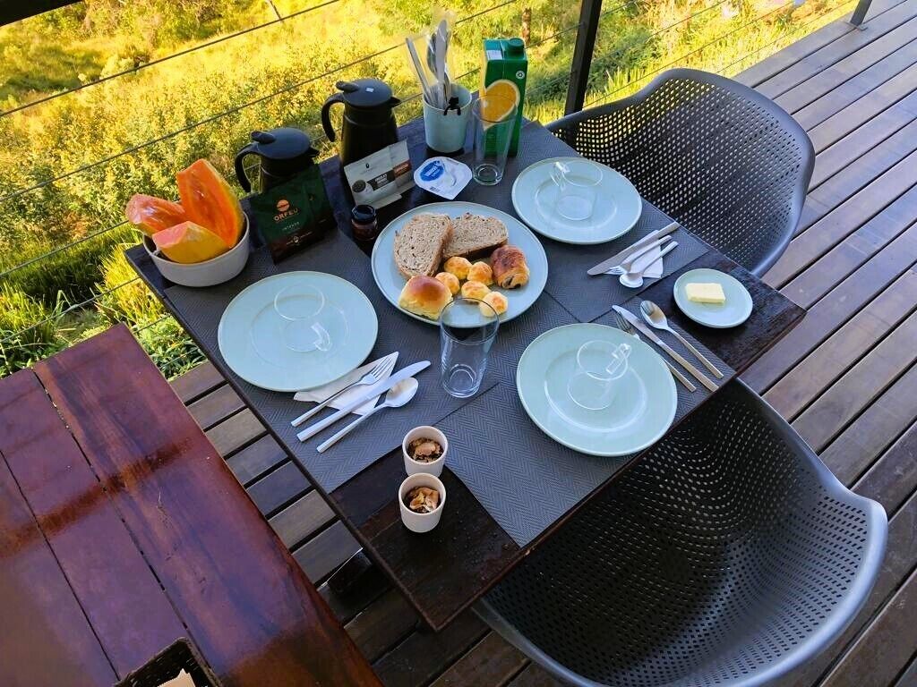 A table set outdoors with plates, cutlery, and a teapot.