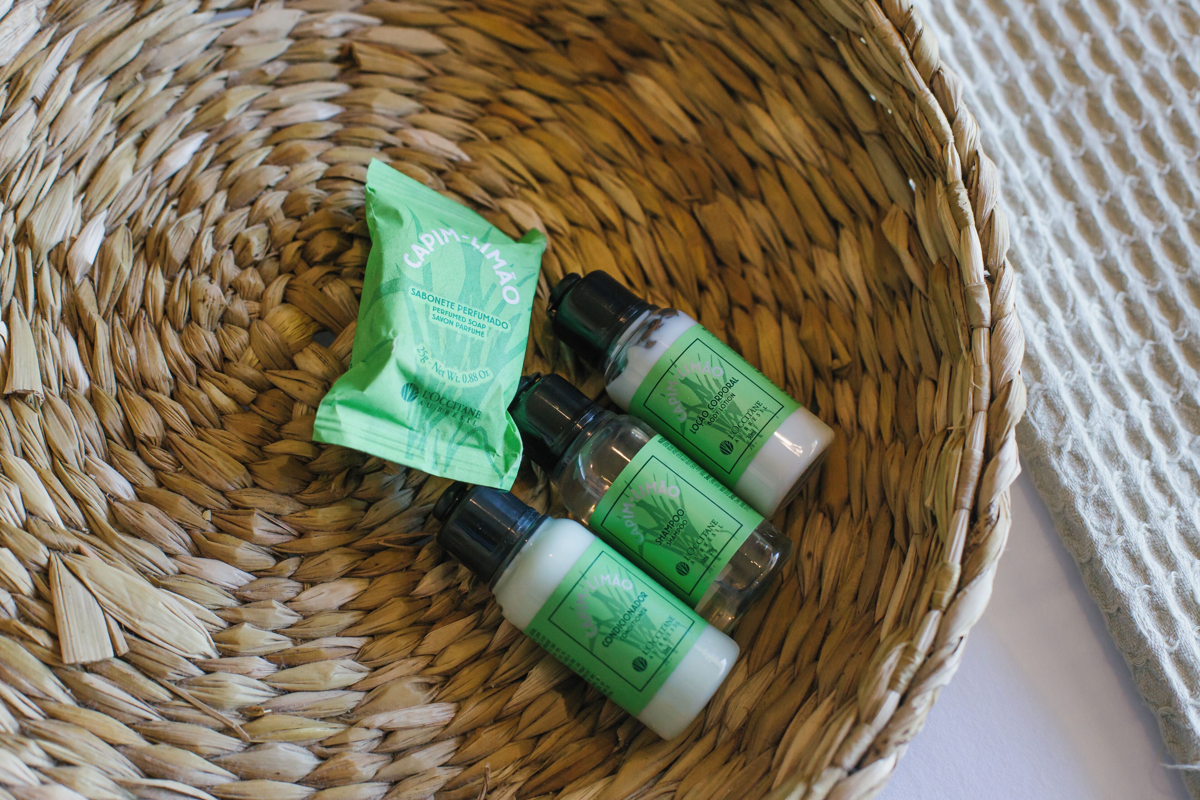 A woven basket containing three bottles of Capim-Lima shampoo and a sachet.