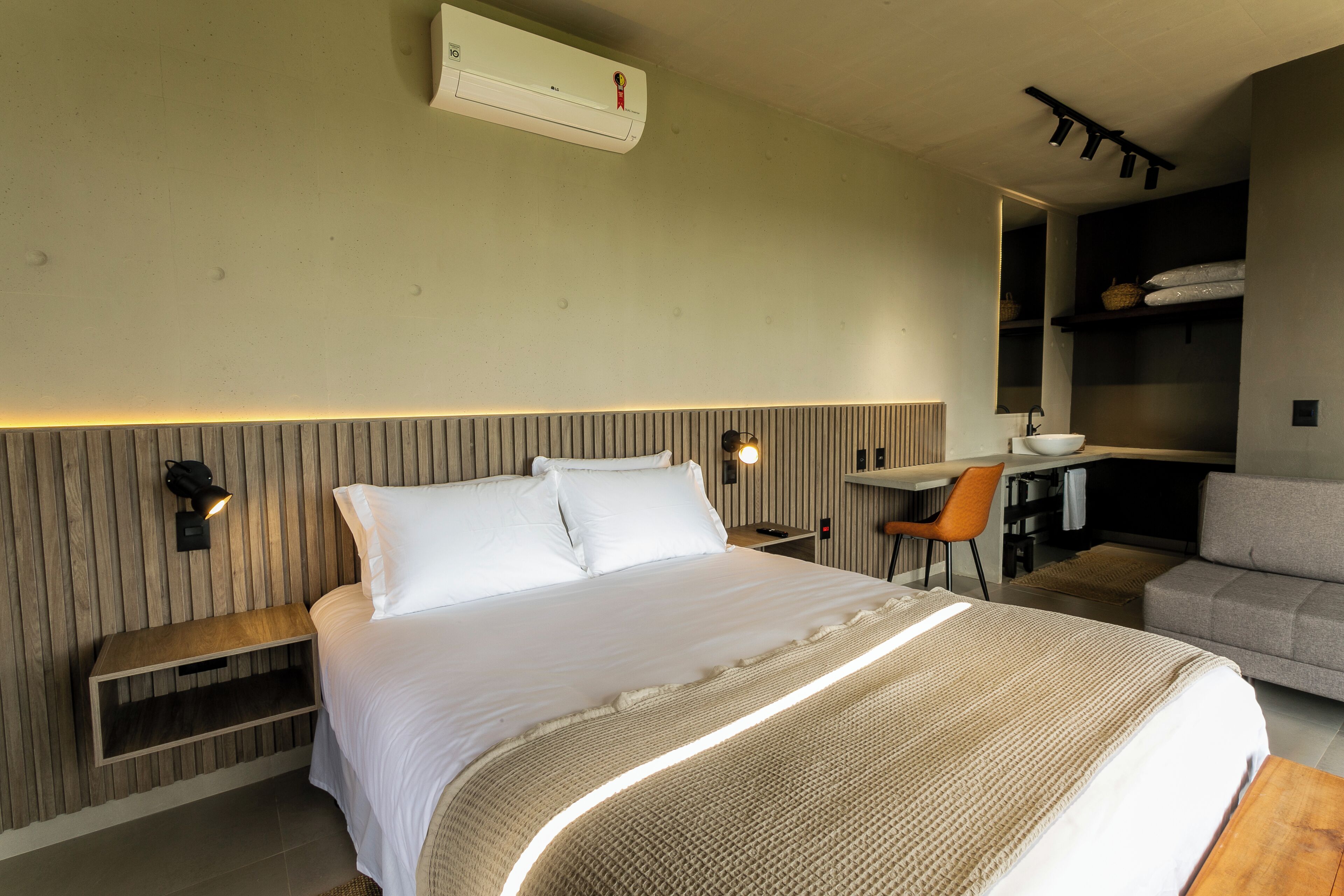Quarto de hotel moderno com uma cama grande, uma mesa e um espaço de estar.
