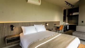 Quarto de hotel moderno com uma cama grande, uma mesa e um espaço de estar.