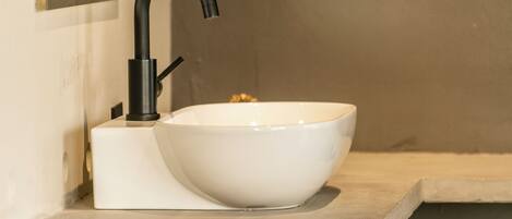 A modern bathroom with a white sink, black faucet, and a rectangular mirror above it.