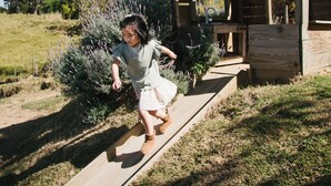 Una estructura de madera con techo inclinado, un banco y un sendero que conduce a ella.