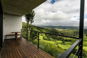 A balcony with a wooden table and bench, overlooking a lush valley with mountains in the distance. - Pousada Casa Bambu Cunha (Cunha)