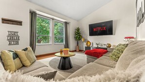 Un salon moderne avec un canapé, une table basse et un téléviseur affichant le logo de Netflix.