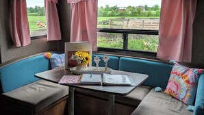 Un interior acogedor con un banco acolchado azul, una mesita con un florero y un libro.